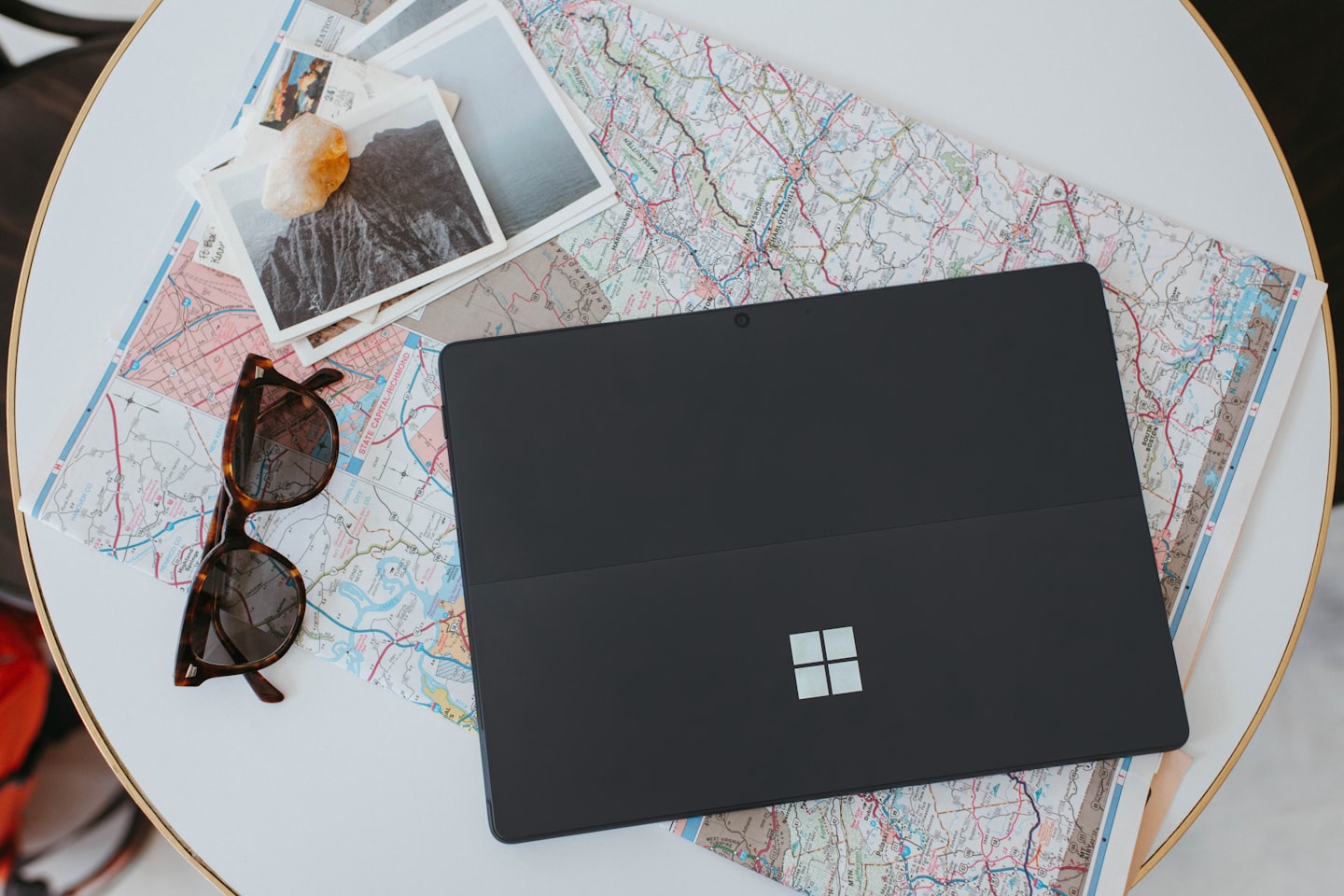 Laptop and travel items laid out on a map for planning a trip.