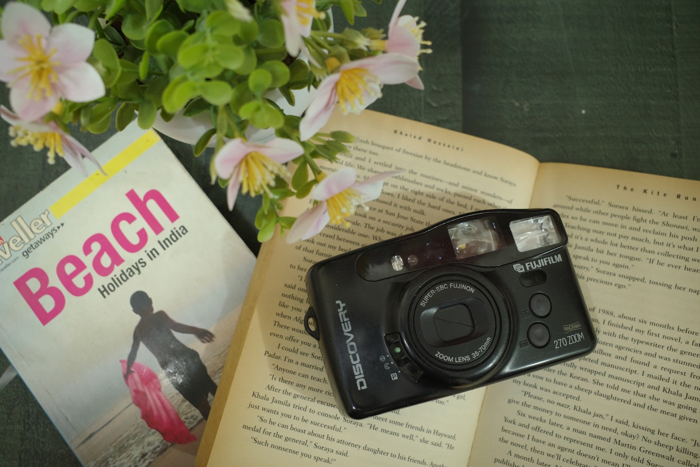 A camera rests on a travel magazine and open book.