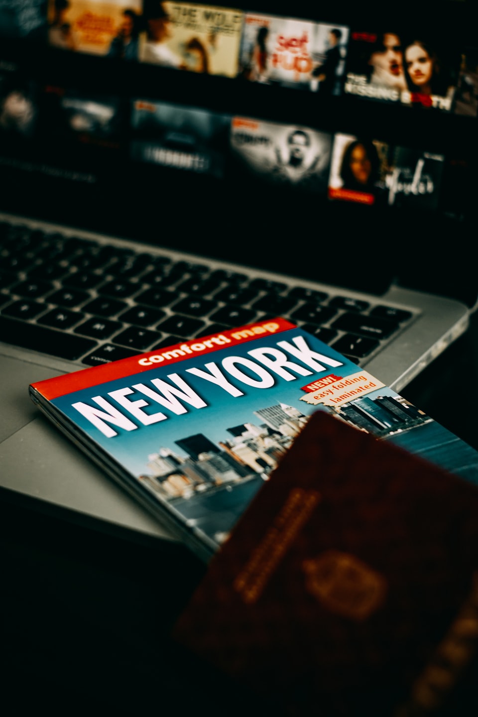 New York travel guide and passport on a laptop.